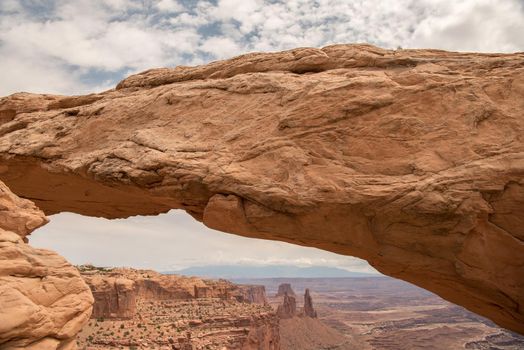 Mesa Arch at Canyonlands National Park with layers of clouds in the background.