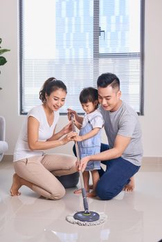 Ordinary family of three doing house cleaning with cleaning equipment