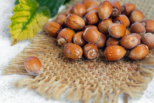 Hazelnuts on a light background with green leaves. Contains beneficial vitamins and minerals.