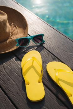 Hat, sunglasses and flip flops by swimming pool
