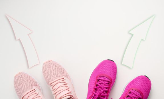 two pairs of pink textile sneakers are directed in opposite directions. Quarrel and difference of opinion concept, different life paths and interests