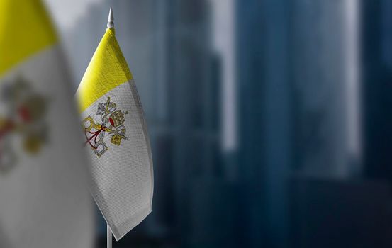 Small flags of Vatican on a blurry background of the city