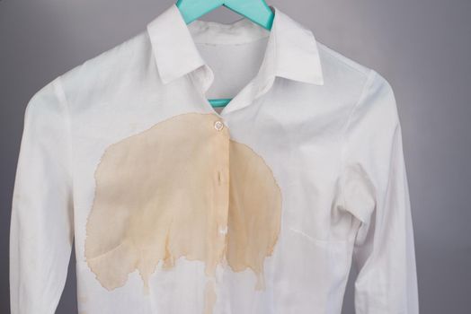 Women's office white shirt with a stain of coffee on a white background.