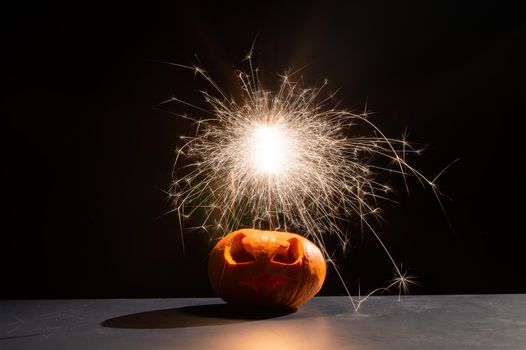 Halloween pumpkin with scary carved grimace and sparklers. jack-o-lantern