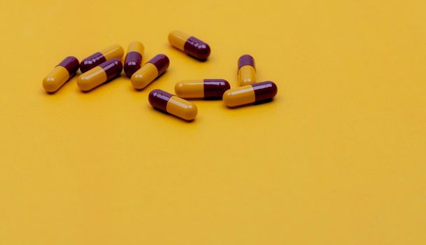 Red-yellow antibiotic capsule pills on yellow background. Prescription drug. Antibiotic drug resistance concept. Penicillin capsule pills. Pharmaceutical industry. Pharmaceutics. Pharmacy product.