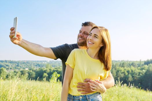 Beautiful happy adult couple taking selfie on smartphone