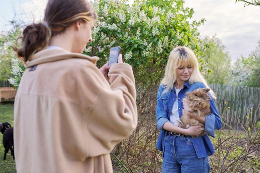 The guy is teenager photographing girlfriend with decorative rabbit in his arms