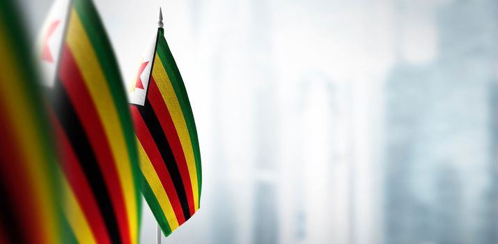 Small flags of Zimbabwe on a blurry background of the city
