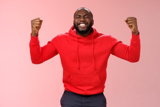 Happy thankful young african american bearded man thank god for son close eyes joyfully smiling clench fists celebrating triumphing dream come true accomplish goal, cheering victory