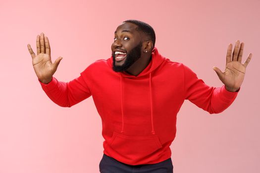 Knock who there. Charming happy funny black bearded guy bending towards camera raised palms move like mime act pressed face glass smiling joyfully fool around playful energized mood