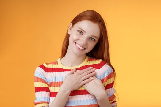 Pleased tender feminine good-looking redhead woman receive compliment confession touch heart feel warmth dearest moment smiling delighted lovely keep love inside soul, standing orange background