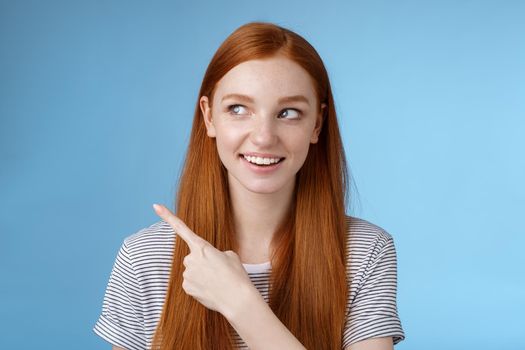 Intrigued good-looking redhead joyful curious girl watching looking upper left corner interested smiling broadly visit cool amusing place explore travelling new country astonished, blue background