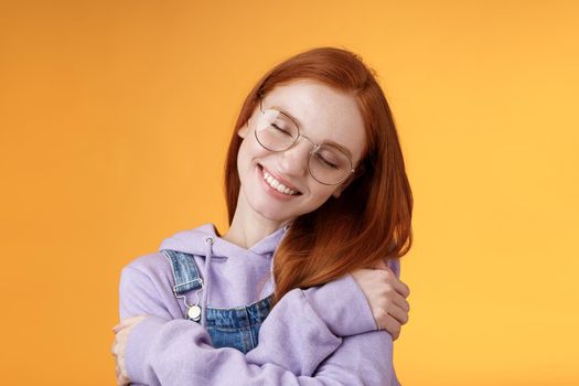 Close-up romantic lovely charming redhead girl enjoy warmth love tilting head close eyes dreamy imaging perfect date hugging herself embracing own body accept body-positivity orange background