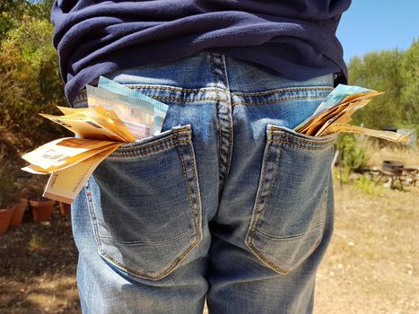 50 and 20 euro banknotes sticking out of the pockets of a blue jeans