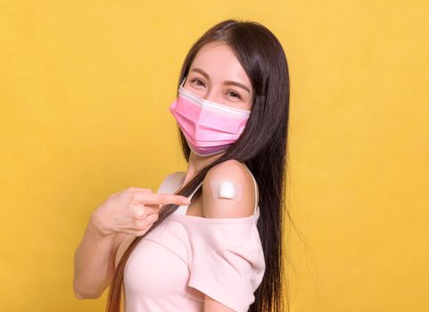Young woman wearing protective mask against covid-19 with showing her arm  after getting vaccine