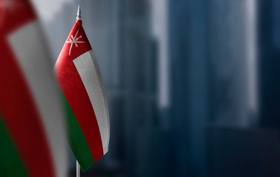 Small flags of Oman on a blurry background of the city
