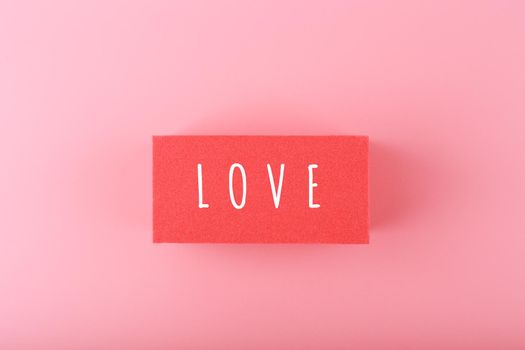 Word love written on red rectangle against pink background with copy space