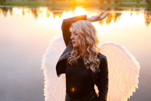 woman with white angel wings. wearing black leather clothes. fallen dark angel. demon. beast. girl in angel costume on halloween