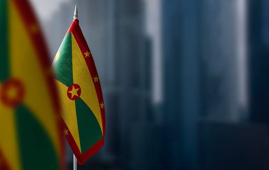 Small flags of Grenada on a blurry background of the city