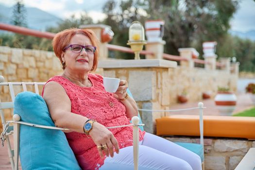 Portrait of beautiful elderly 70s woman relaxing with cup.