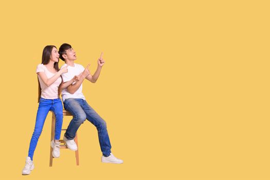 happy excited Asian couple  pointing hands to empty space