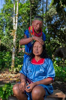 Elderly indigenous shaman of Cofan nationality performing healing ritual to a Cofan woman in the Amazon rainforest