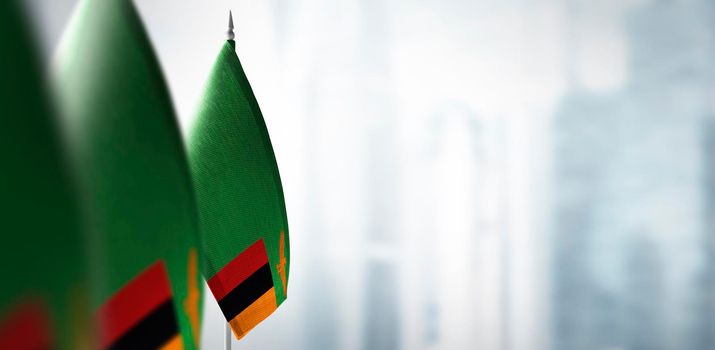 Small flags of Zambia on a blurry background of the city