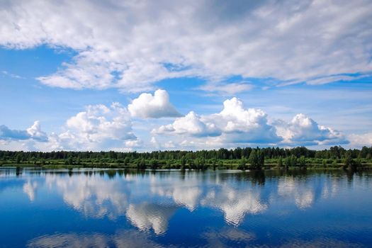 Summer landscape with clouds reflected in river or lake water surface