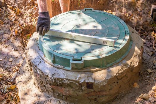 Installation of a septic tank with a well made of concrete rings. Leveling the hatch cover