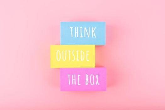 Creativity concept. Think outside the box written on colorful rectangles on bright pink background