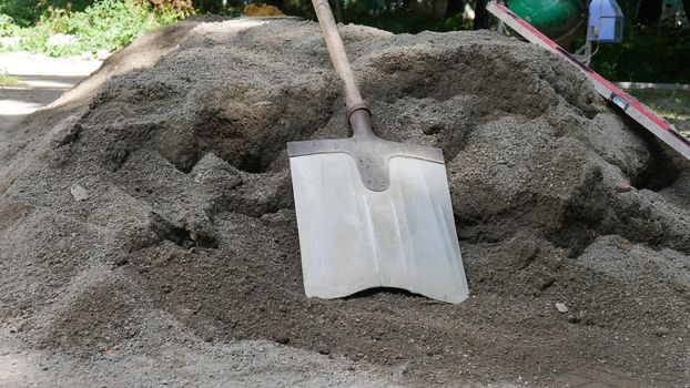 The shovel for dripping is lying on the pile of dry concrete or cement, construction and development concept