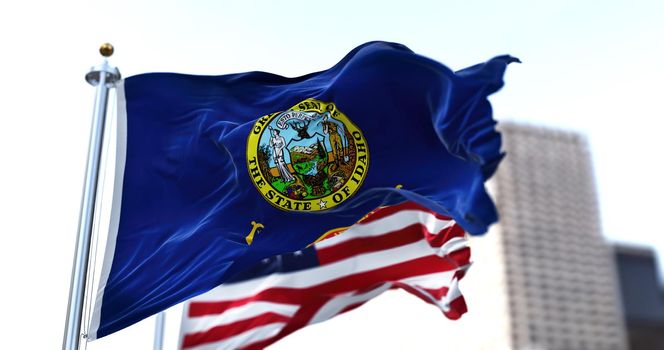 the flag of the US state of Idaho waving in the wind with the American stars and stripes flag blurred in the background