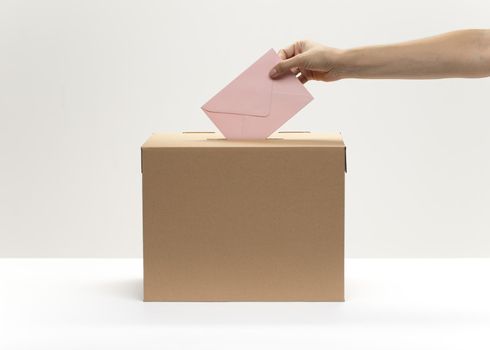 hand puts pink envelope into vote box. High quality beautiful photo concept