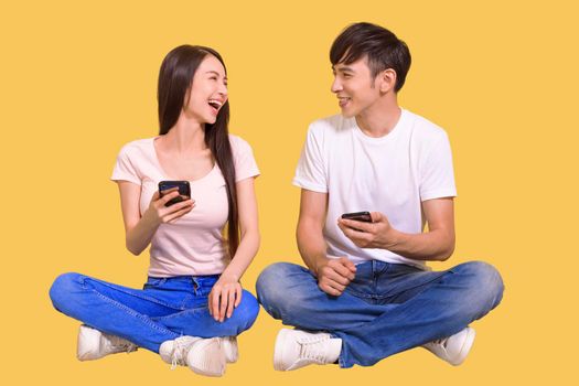 Cheerful young asian couple sitting on floor