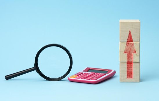 magnifier and calculator on a blue background. Income and expense growth concept