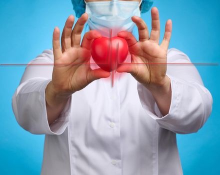 doctor in a white medical coat holding a red heart. Cardiovascular disease concept, early diagnosis. Blue background
