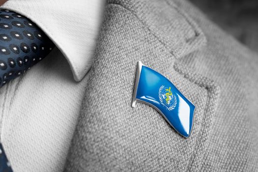 Metal badge with the flag of World Health Organization WHO on a suit lapel