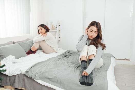 beautiful young female friends having serious quarrel and feeling angry  ignore each other in bedroom