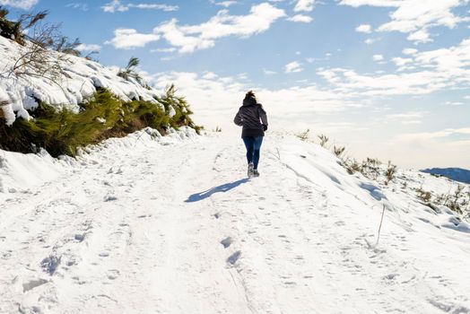 Young traveler woman jogging on snowed mountain