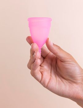 close up hand holding pink menstrual cup. High quality photo