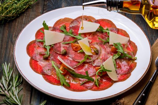 Beef carpaccio with Parmesan and arugula on plate