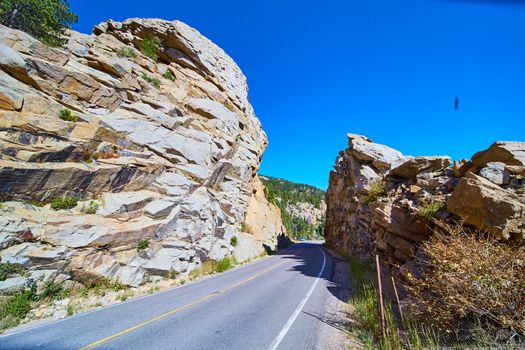 Road going through rocky mountain with large rock cliffs