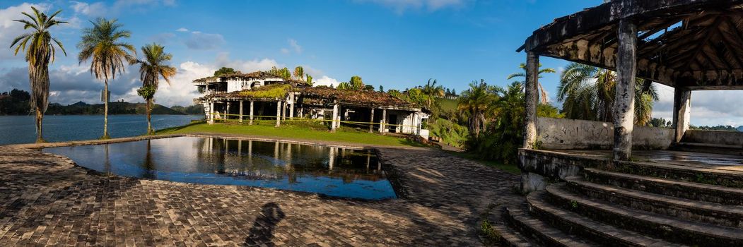 Pablo Escobar's old estate La Manuela in ruin with palm trees pool and river in view. Panoramic view
