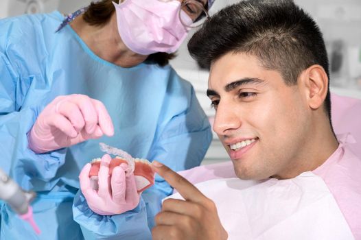 Dentist shows invisible braces aligner. Dental consultation in an orthodontic clinic