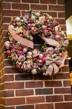 Creative Christmas wreath with pink flowers bulbs and ribbon.