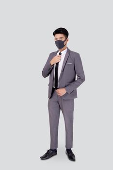 Portrait young asian businessman in suit wearing face mask for protective covid-19 isolated on white background, business man hand holding neck tie, quarantine for pandemic coronavirus, new normal.
