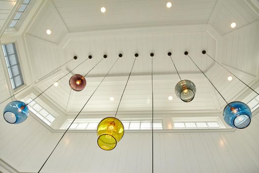 Multicolored glass globes with light bulbs inside hang from a skylight