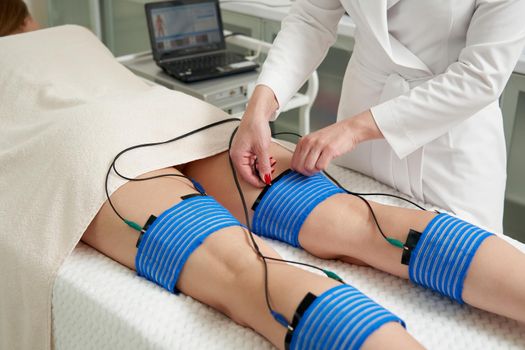 The procedure of myostimulation on legs of a woman in a beauty salon. Caring for the body with electrostimulation, reducing excess weight
