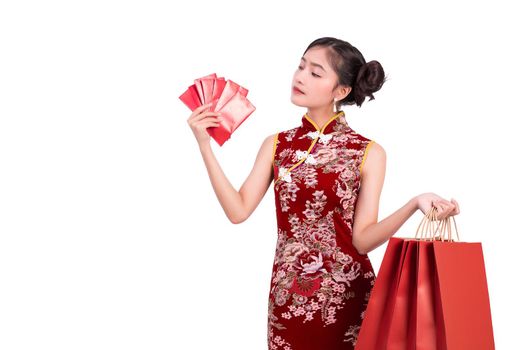 Young Asian beauty woman wearing cheongsam and holding moneys as millionaire gesture in Chinese new year festival event on isolated white background. Holiday and Lifestyle concept. Qipao dress wearing