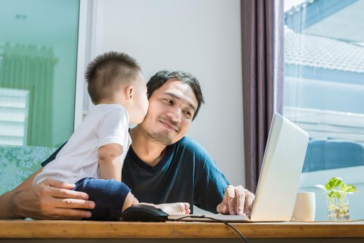Son kissing his father while using internet. People and Lifestyles concept. Technology and Happy family theme. Single dad theme.